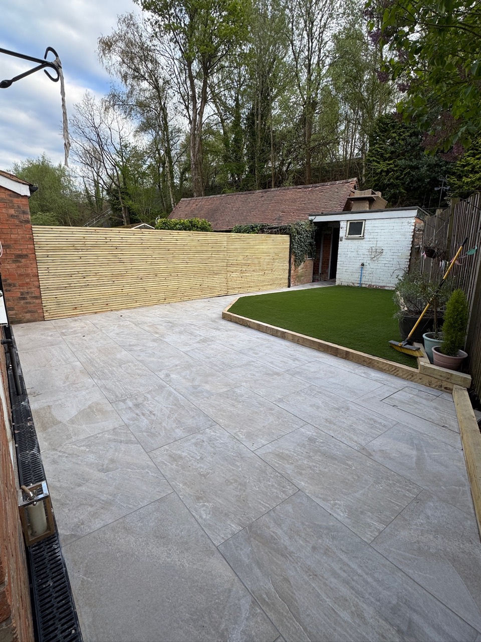 After: grey paving, horizontal timber screening and a neatly edged lawn area
